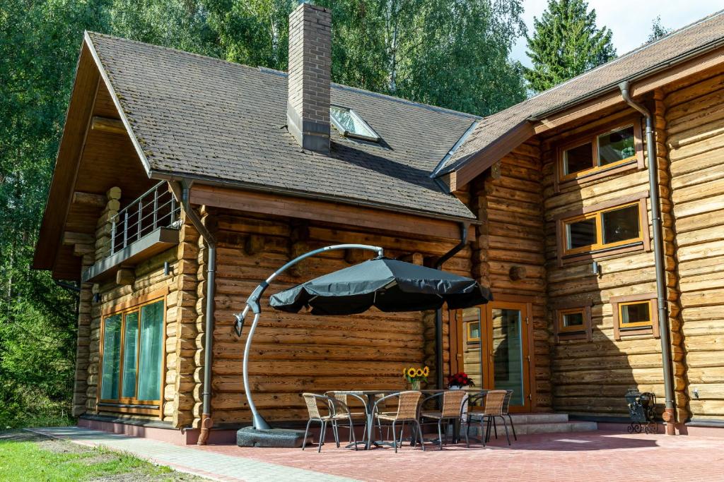 a log cabin with a table and chairs and an umbrella at Villa Rose & SPA in Mežciems