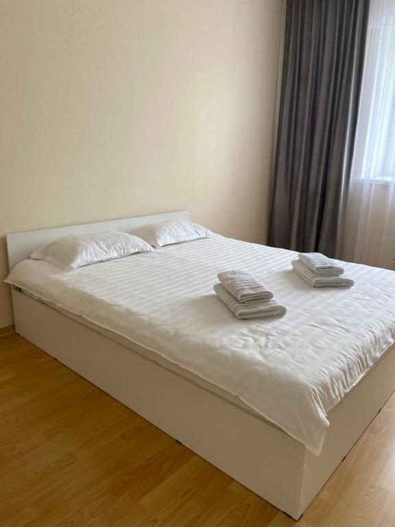 Una cama blanca con dos toallas encima. en Апартаменты в центре города, en Astana