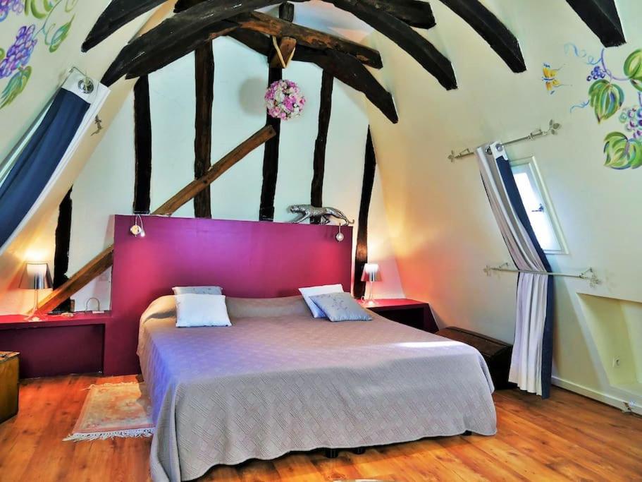a bedroom with a large bed with a purple headboard at Cité médiévale, charme & calme, bien placé in Sarlat-la-Canéda