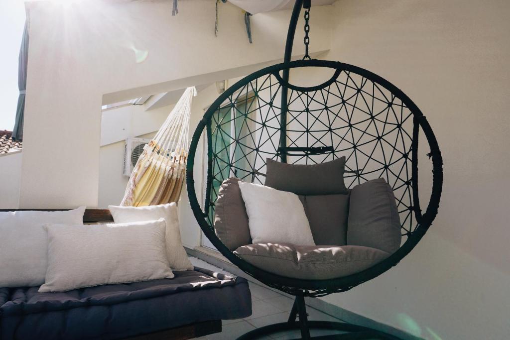 uma cadeira suspensa com almofadas numa sala de estar em Chez Louise: onde a Serra beija o Céu em Lousã