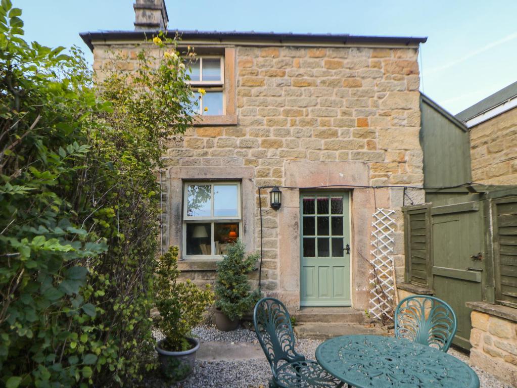 a stone house with a table and chairs in front of it at Clematis Cottage in Bakewell