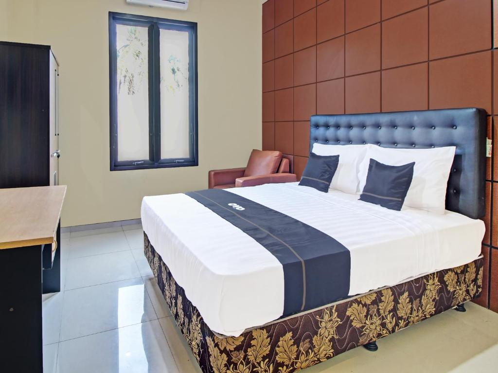 a bedroom with a large bed and a chair at Collection O 91666 Meyli Guesthouse in Cilacap