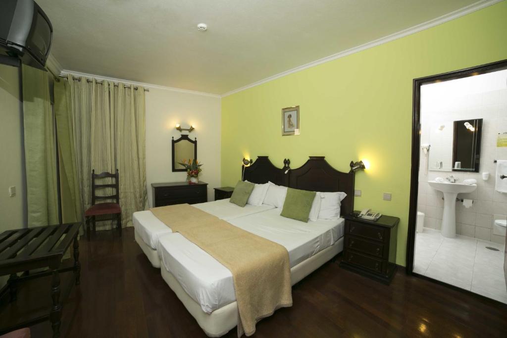 a bedroom with a large white bed and a sink at Hotel Sirius in Funchal
