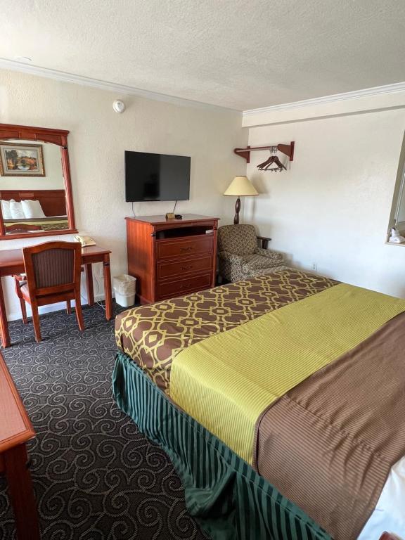 ハンフォードにあるAmericas Best Value Inn Hanfordのベッドとデスクが備わるホテルルームです。
