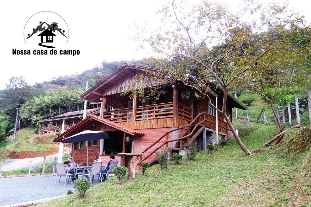 a house on a hill with people sitting in front of it at Nossacasa-de-campo in Blumenau