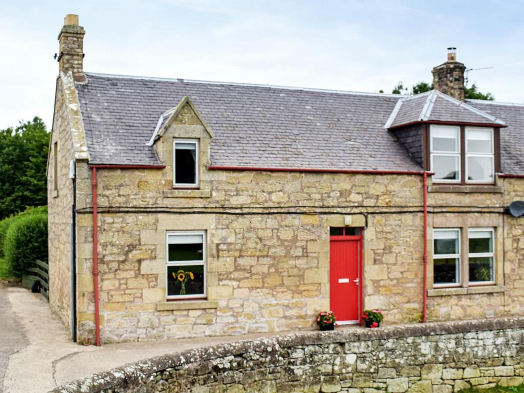 a stone house with a red door at The End Hoose in Whitsome