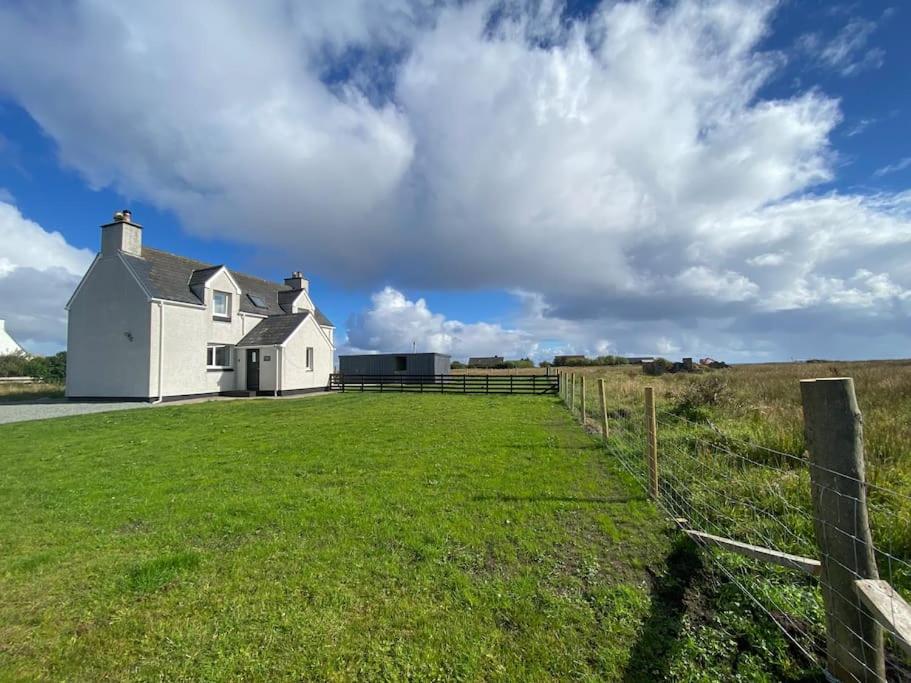 a white house in a field with a fence at Kinnoull House near Stornoway Hot Tub/Pet Friendly in Garrabost
