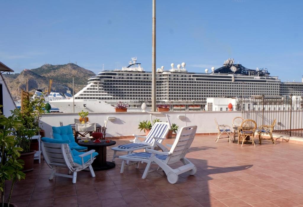 a balcony with chairs and a cruise ship in the background at Attico con terrazza sul porto in Palermo