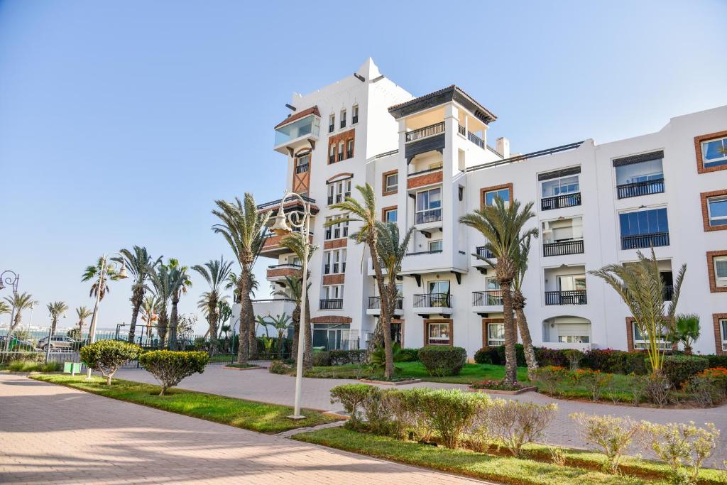 um edifício de apartamentos branco com palmeiras e um passeio em Marina Agadir Sunny Holiday em Agadir