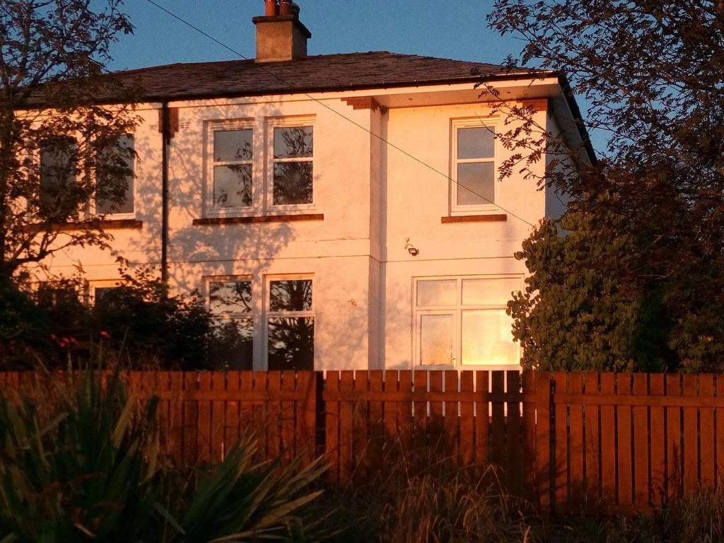 une maison blanche avec une clôture devant elle dans l'établissement Buckieburn, à Banknock