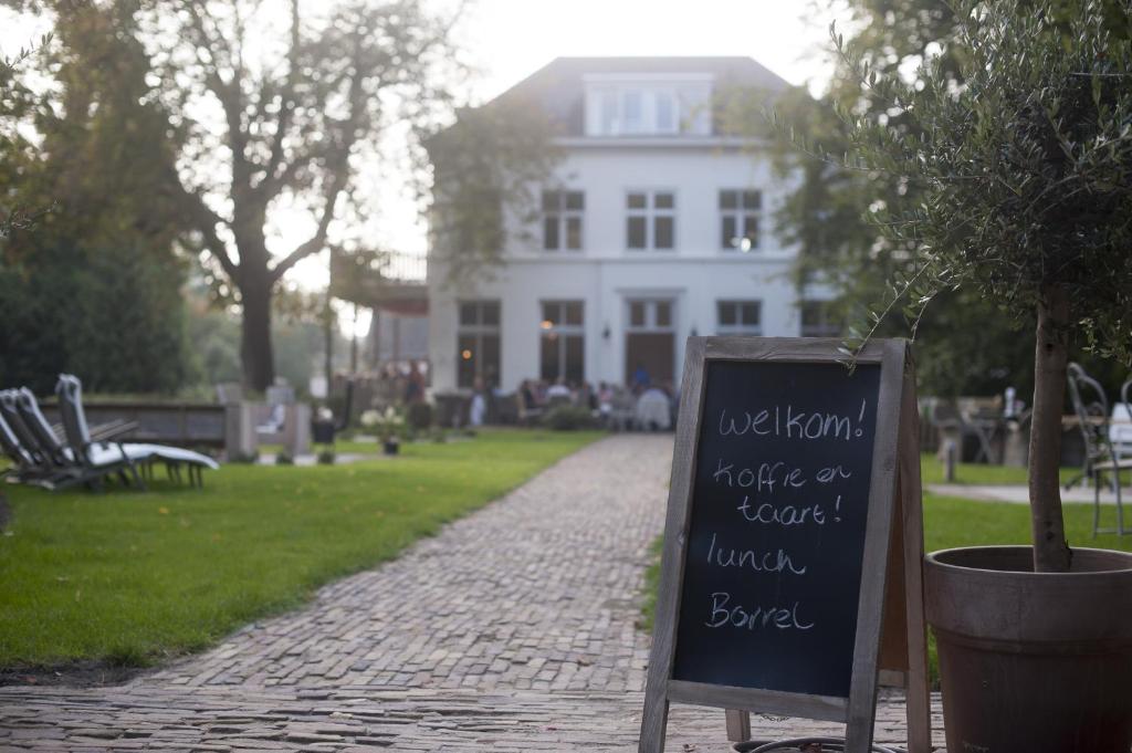 a chalkboard sign in front of a white house at Boutique B&B Villa Heidetuin in Bergen op Zoom