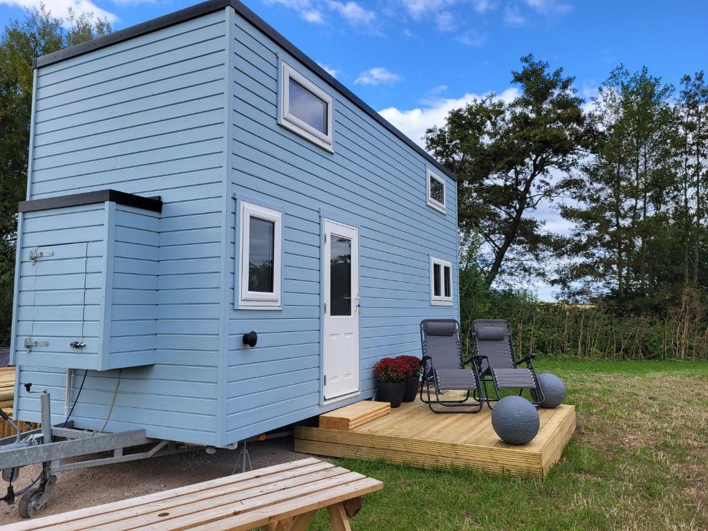 a blue tiny house with two chairs on a deck at Bracken Heights in Newark-on-Trent