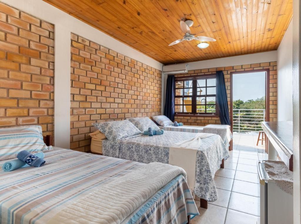 Un dormitorio con dos camas y una pared de ladrillo. en Pousada Baleia Franca, en Garopaba