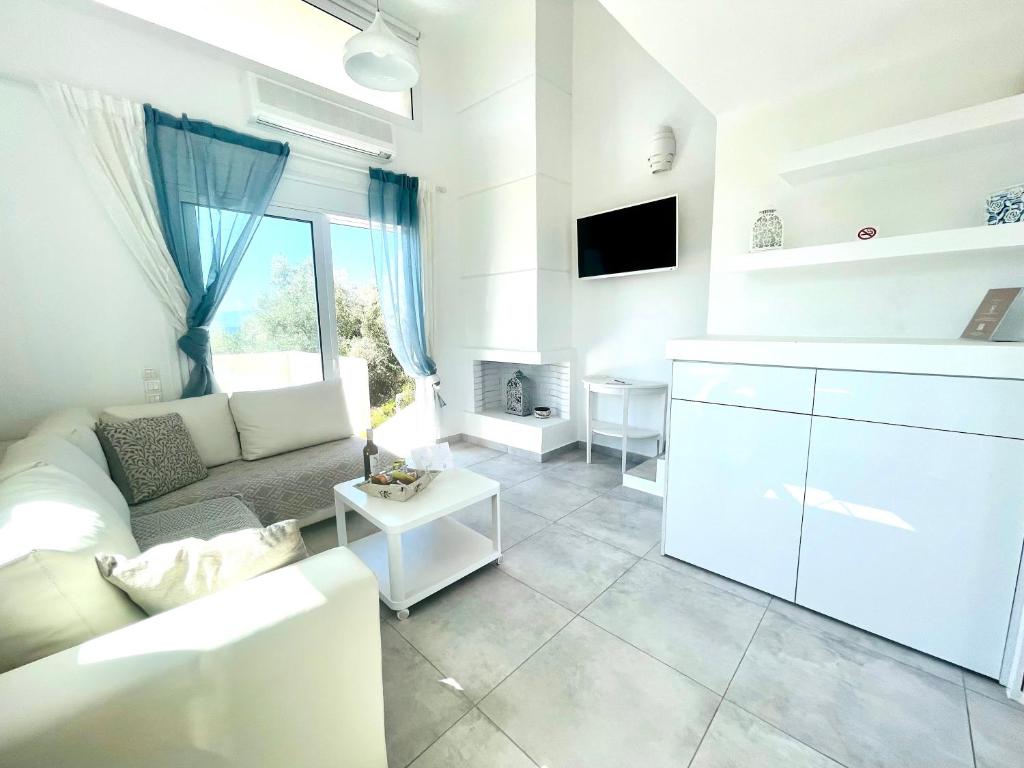 un soggiorno bianco con divano e tavolo di Syllas Grand Resort - Prestigious Villa 8 a Edipsos