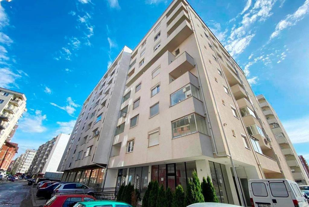1-Bedroom Apartment Fushë Kosovë في Kosovo Polje: مبنى طويل وبه سيارات متوقفة أمامه