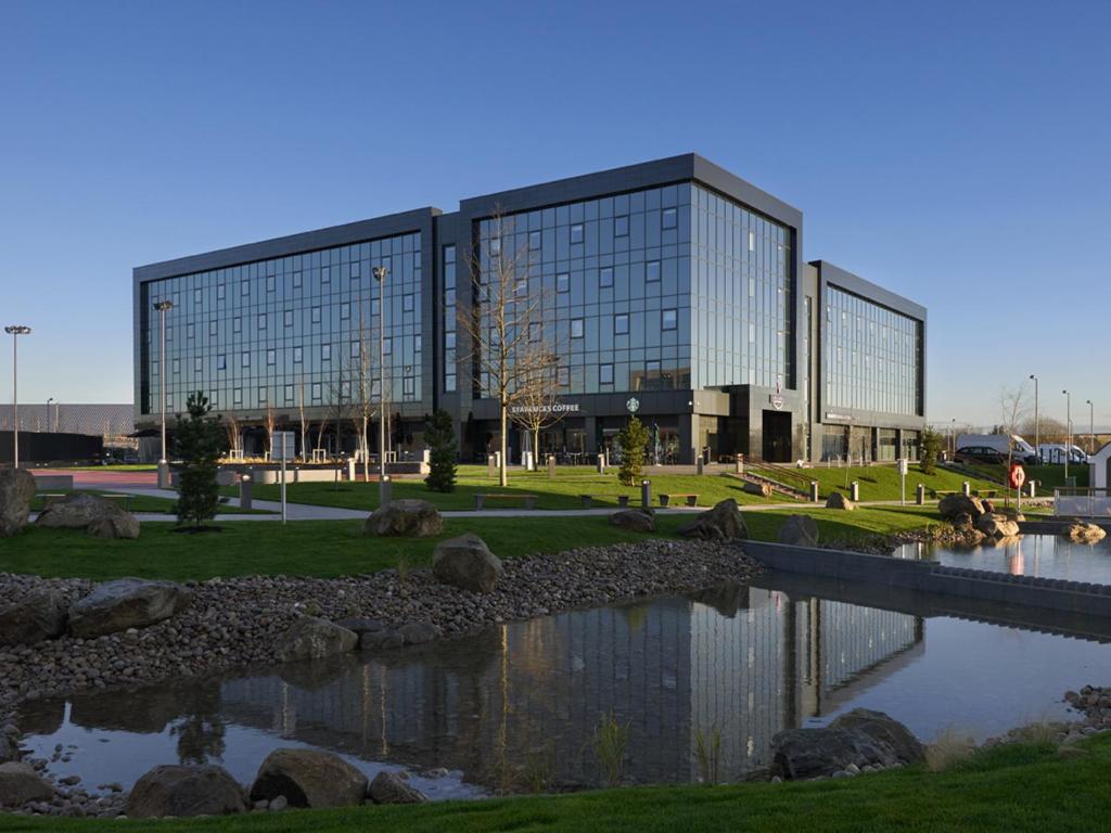 a large glass building with a pond in front of it at Village Hotel Aberdeen in Aberdeen