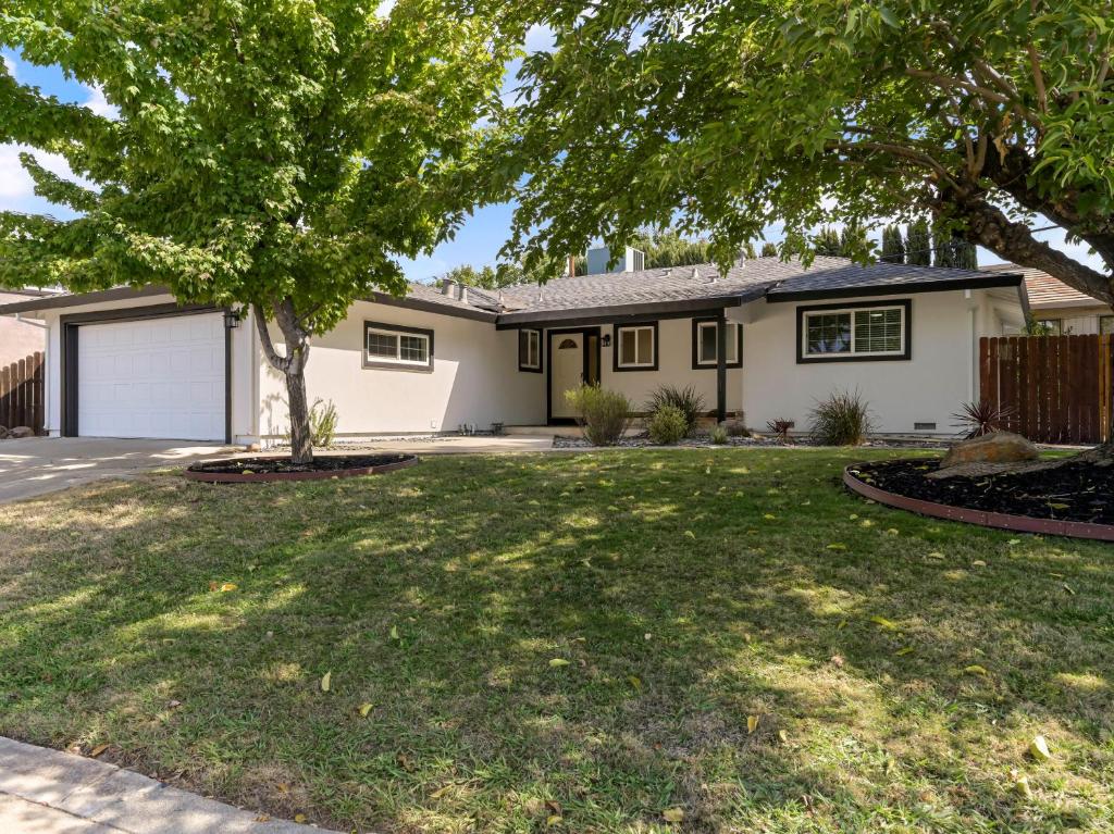 a house with a tree in the yard at Fully Renovated 4 Bedroom Home with Pool! in Roseville