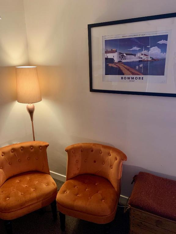 a living room with two chairs and a lamp at Lochindaal Hotel in Port Charlotte