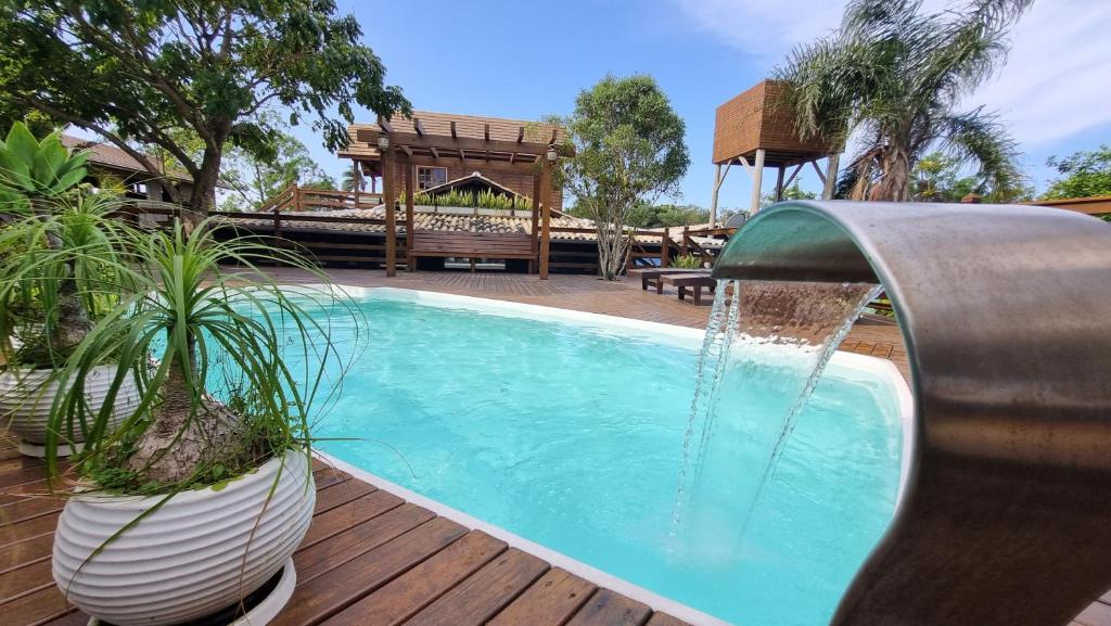uma piscina com uma fonte de água em Arte da Tribo Hostel & Camping na Praia do Rosa