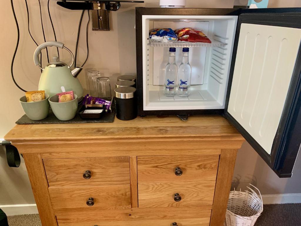 a microwave on top of a wooden dresser with drinks in it at Lochindaal Hotel in Port Charlotte