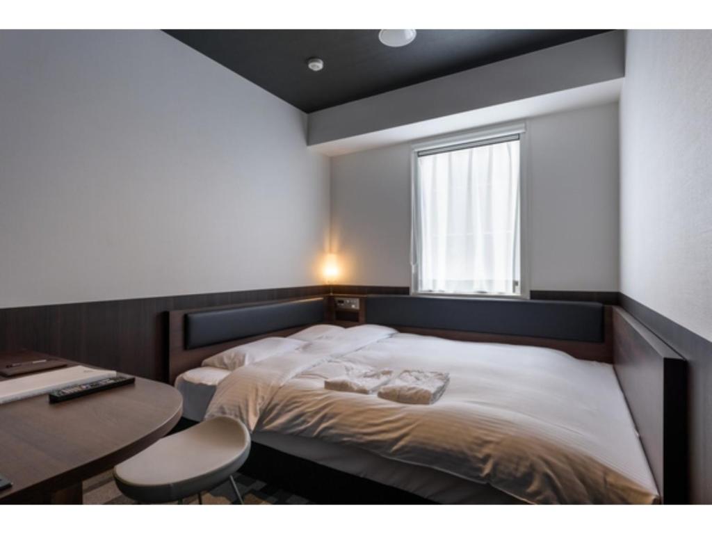 a bedroom with a bed and a desk and a window at Belken Hotel Kanda - Vacation STAY 80890v in Tokyo