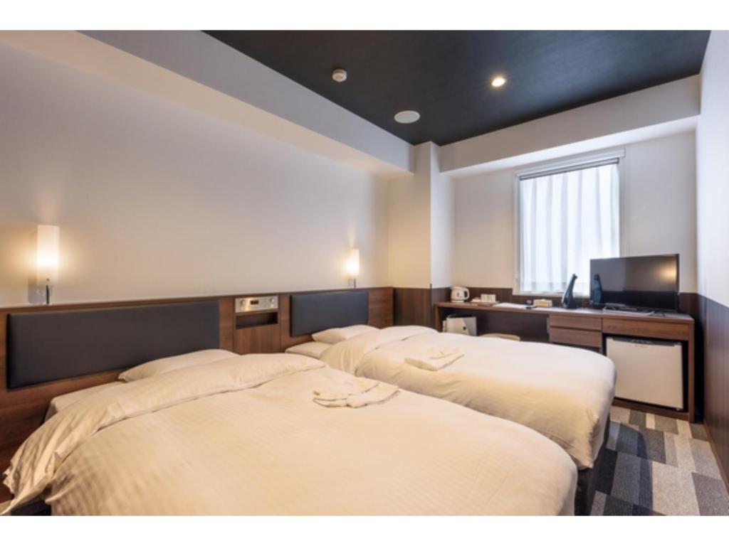 two beds in a room with a desk and a television at Belken Hotel Kanda - Vacation STAY 80921v in Tokyo