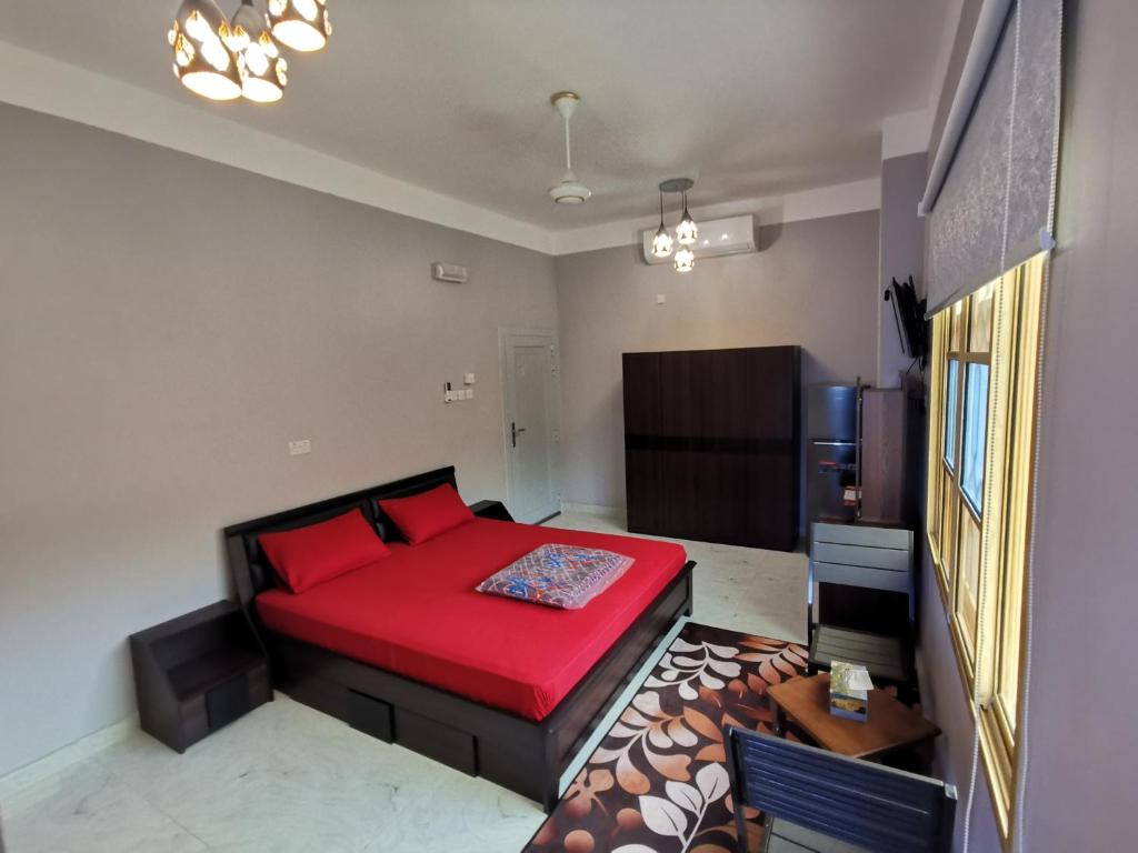 a bedroom with a red bed in a room at Al Hamra Guest House in Al Ḩamrāʼ