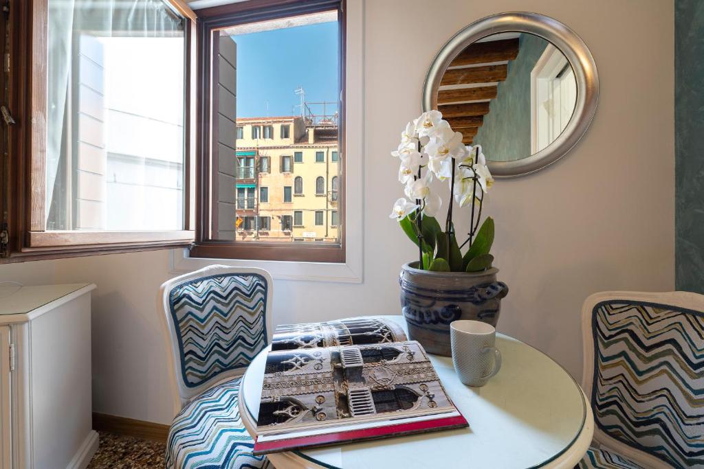 Residenza San Silvestro في البندقية: غرفة مع طاولة وكراسي ومرآة