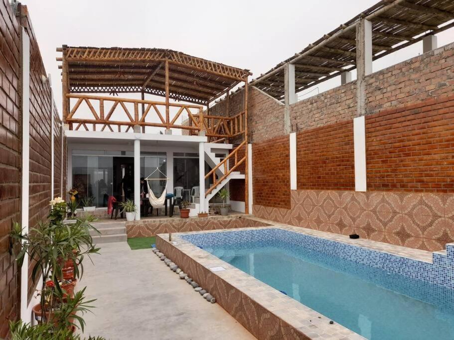 een huis met een zwembad en een bakstenen muur bij CASA PLAYA REFUGIO AZUL in Cerro Azul