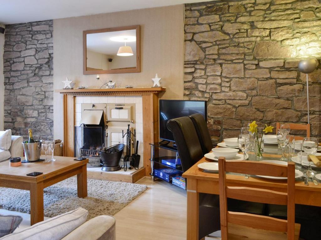 ein Wohnzimmer mit einem Tisch und einer Steinmauer in der Unterkunft Baldowrie Farm Cottage in Ardler