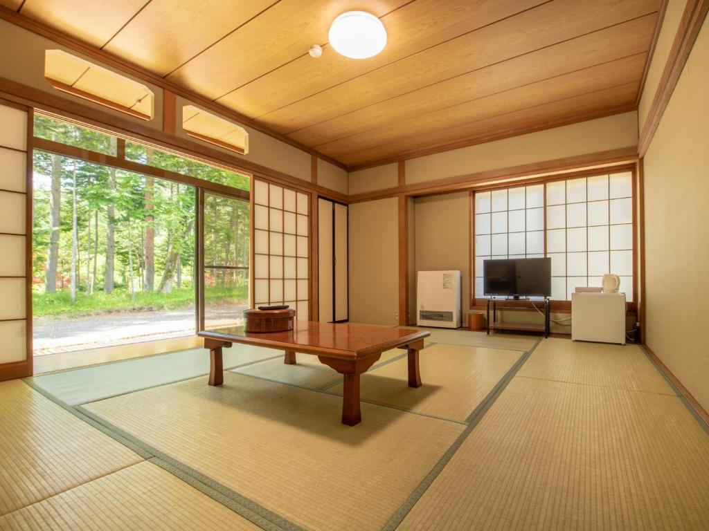 a living room with a table and a tv at Yamanaka Lake ＲＹＯＺＡＮ - Vacation STAY 32157v in Yamanakako