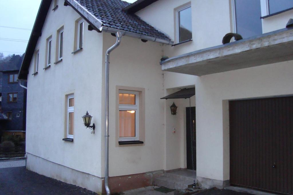 a white house with a door and a garage at Ferienwohnung Burgruine in Rauenstein