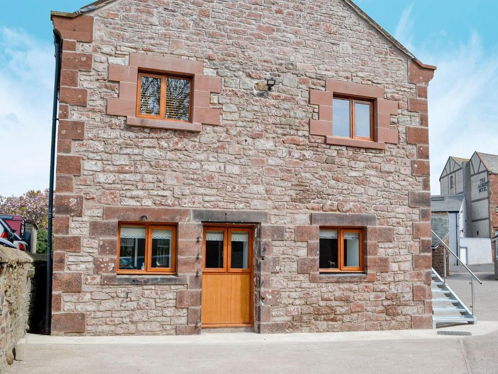 a brick building with orange doors and windows at The Byres Tan in St Bees