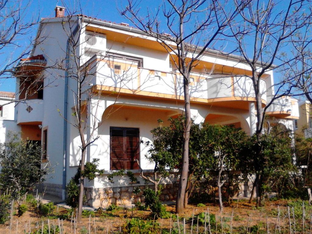 una casa blanca con árboles delante de ella en Apartments Krešimir beauty with shadow trees and parking place, en Pag