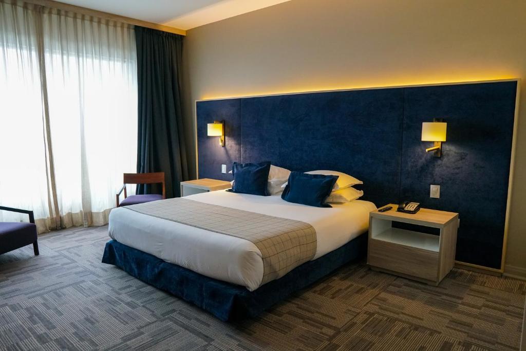 リナレスにあるHotel Parada Linaresの青い壁の大型ベッドが備わるホテルルームです。