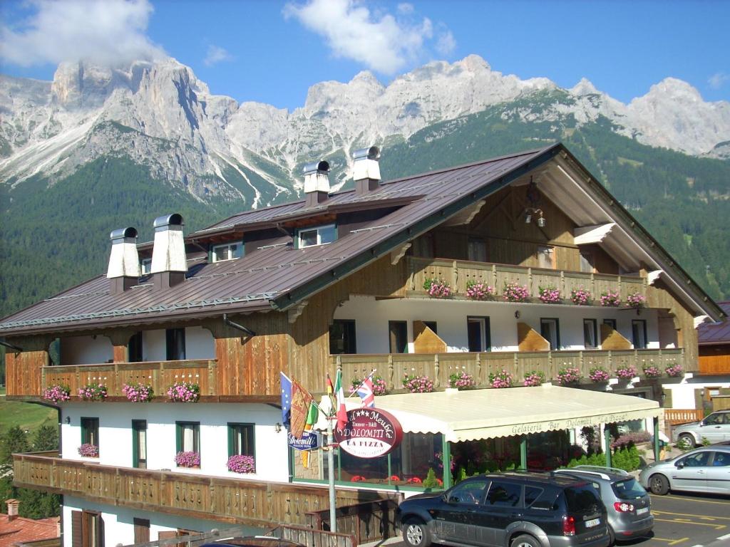a large building with mountains in the background at HOTEL DOLOMITI di De Martin D Oscar in Comèlico Superiore