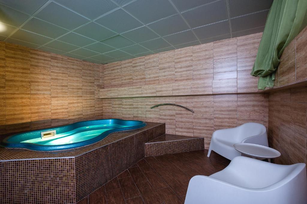 a bathroom with a tub and two white chairs at Villa LUI-JO in Krasnodar