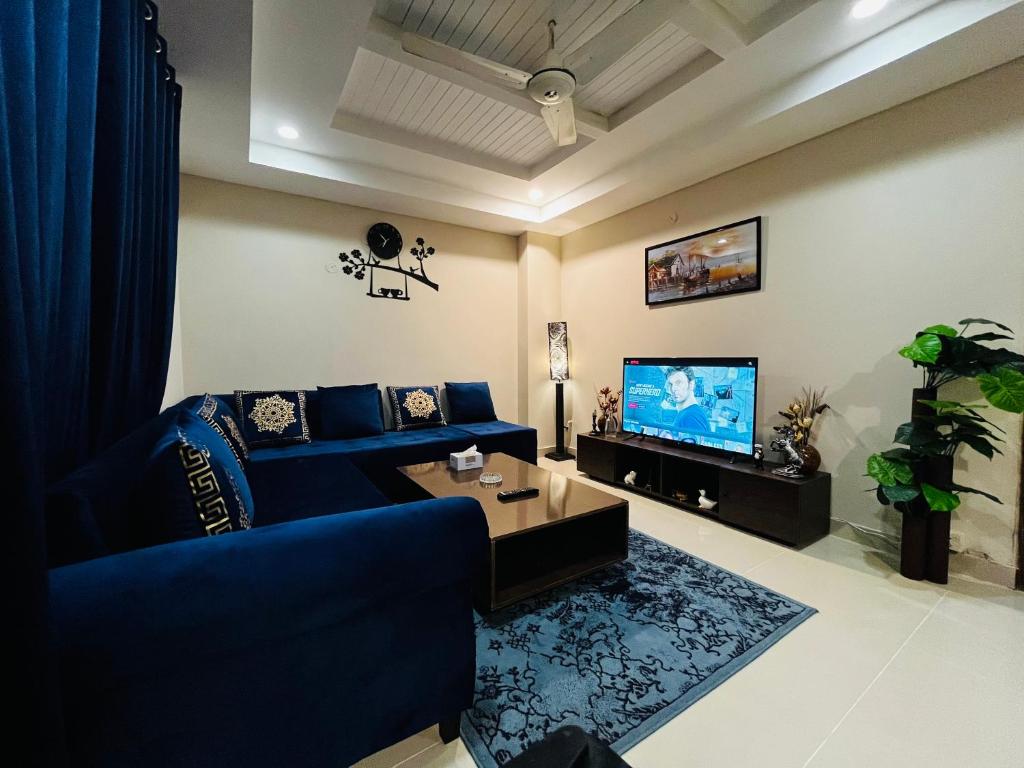 a living room with a blue couch and a tv at Entire 1 BR Apartment: Netflix, Youtube. in Islamabad