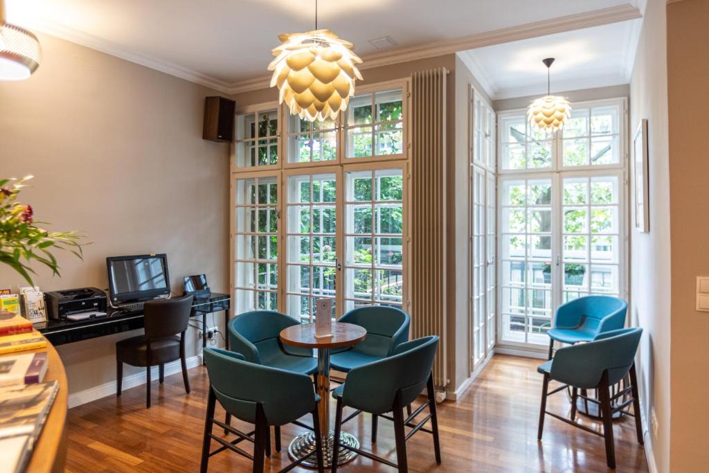 een eetkamer met een tafel, stoelen en ramen bij Hotel Spiess & Spiess in Wenen