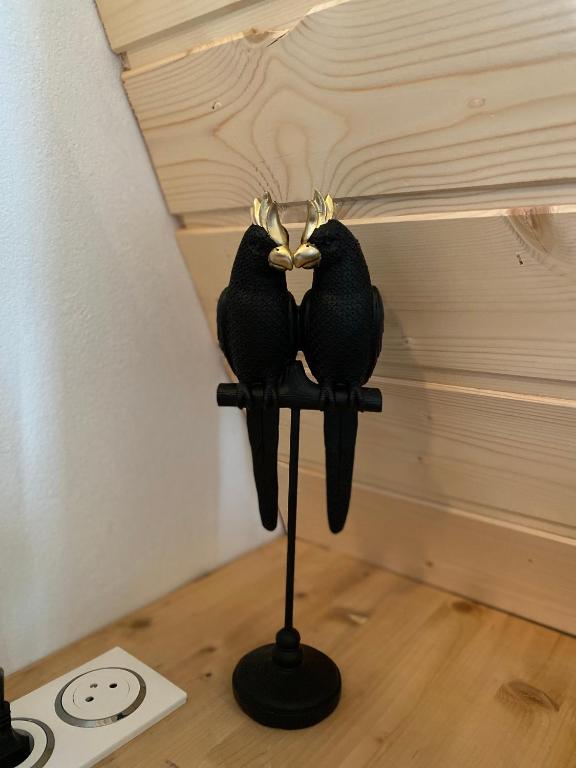 two birds sitting on a stand in a room at Au-Doux-Altic chalet romantique avec JACUZZI ET SAUNA in Métabief