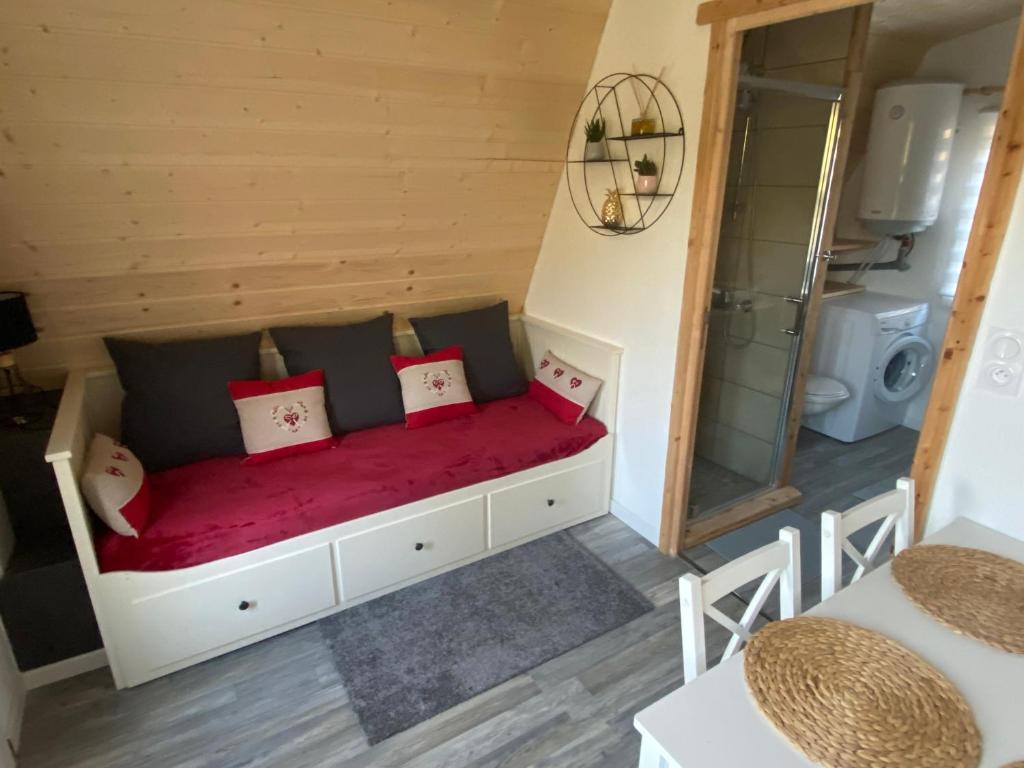 a small bedroom with a red bed in a room at Au-Doux-Altic chalet romantique avec JACUZZI ET SAUNA in Métabief