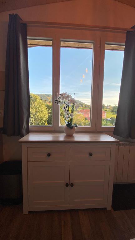 a room with two windows and a table with a flower on it at Au-Doux-Altic chalet romantique avec JACUZZI ET SAUNA in Métabief