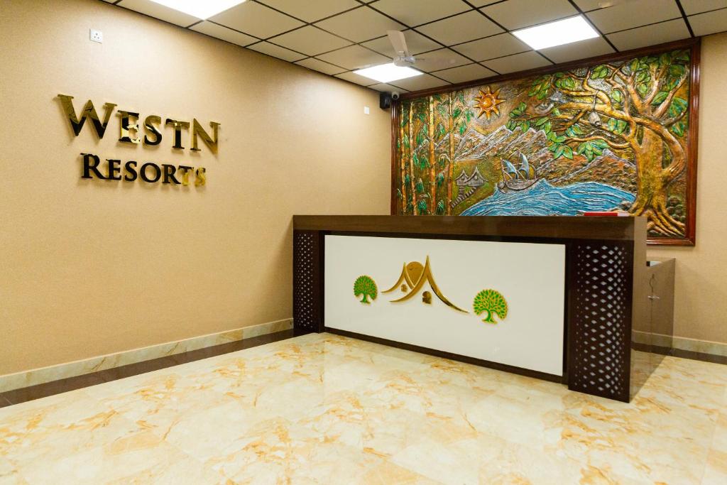 una zona de recepción de un complejo westin con una pintura en la pared en WESTN Resorts en Kuttālam