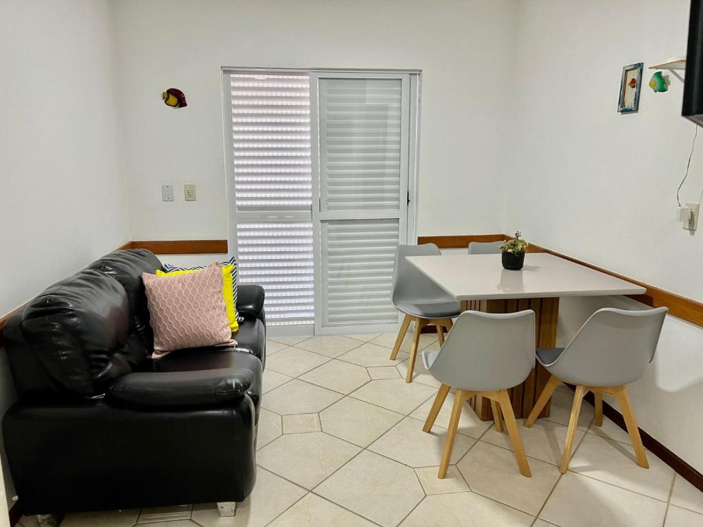een woonkamer met een zwarte leren bank en een tafel bij Sal De Mariscal 02 in Bombinhas