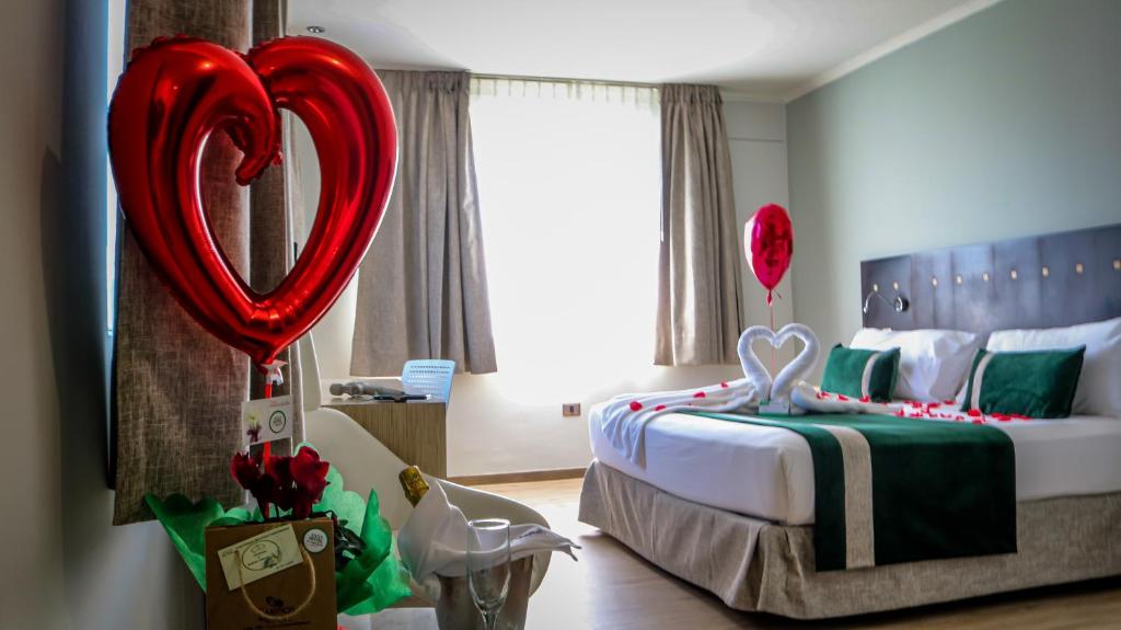 a bedroom with a bed with red heart balloons at Ecohotel Talca in Talca