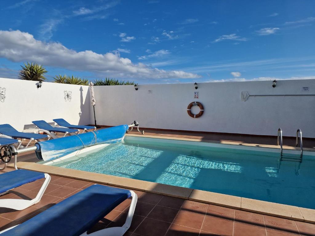 einen Pool mit Liegestühlen und einem Pool in der Unterkunft Villa Georgiana - 4 Bed Property with private pool in Playa Blanca
