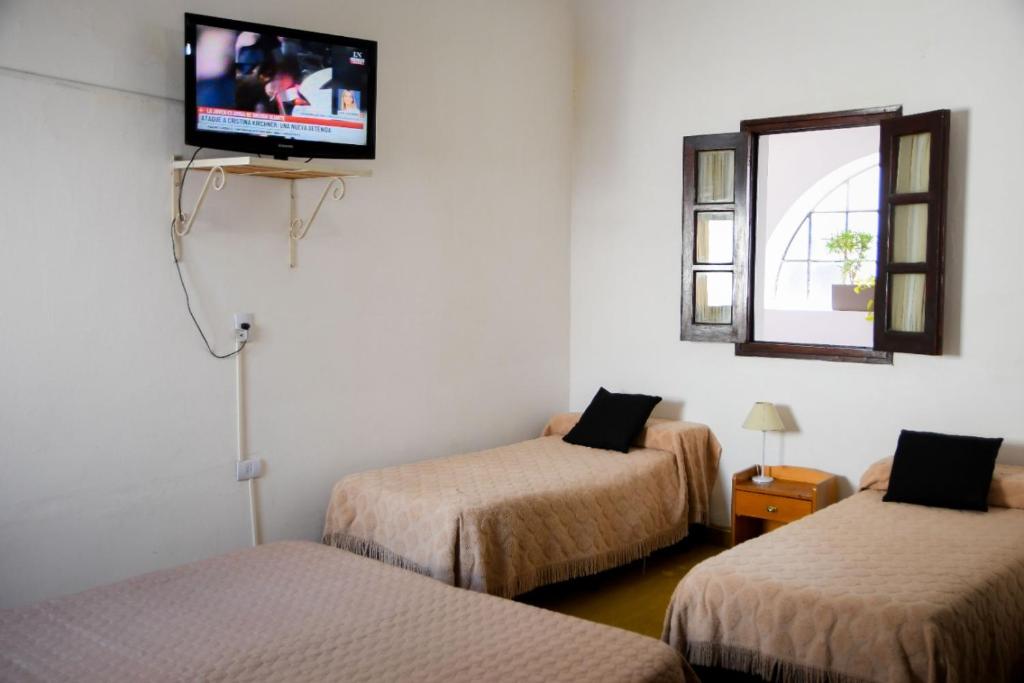 Habitación con 2 camas y TV en la pared. en Hotel Cervantes en Termas de Río Hondo