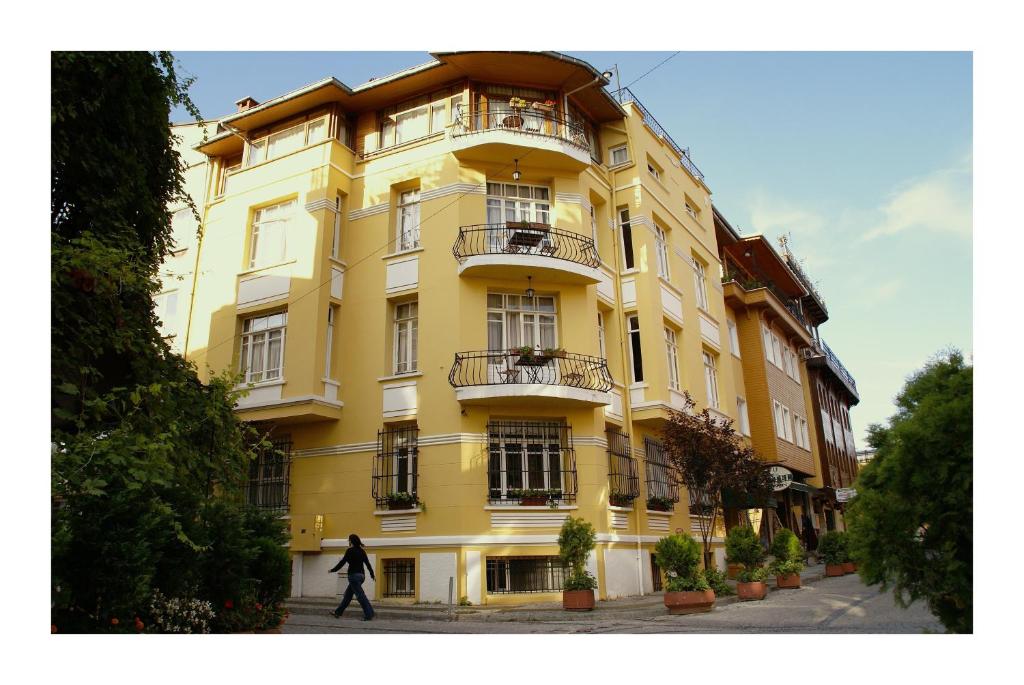a person walks past a yellow building at Hotel Uyan-Special Category in Istanbul