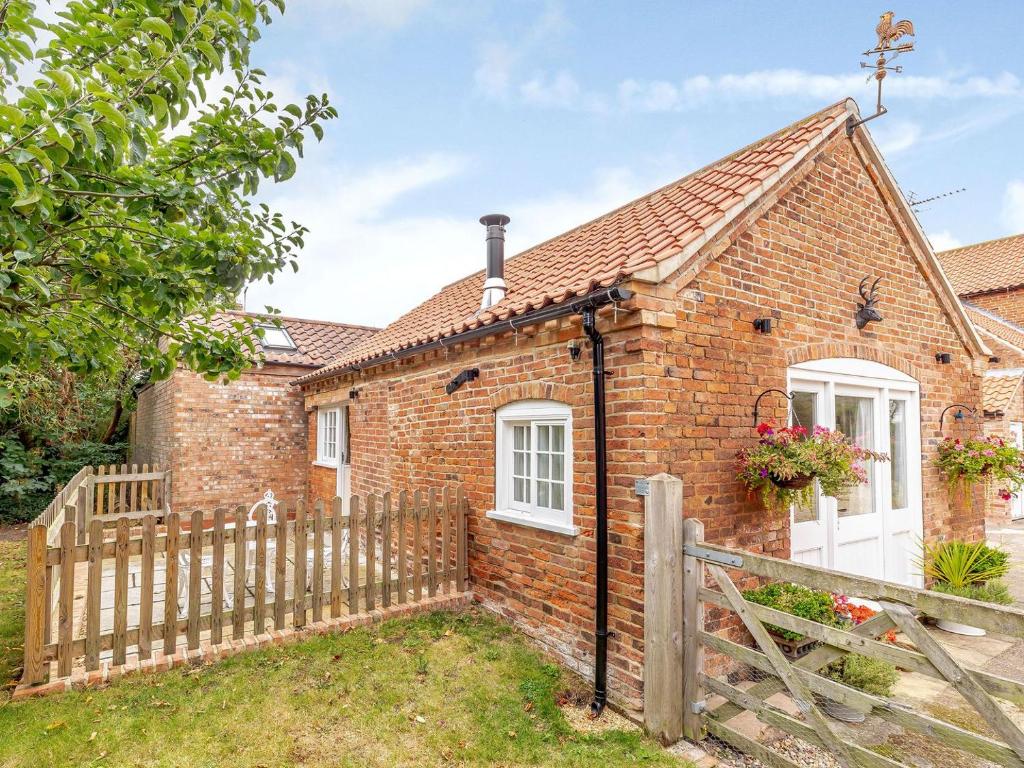 a brick cottage with a wooden fence in front of it at The Croft in Laneham