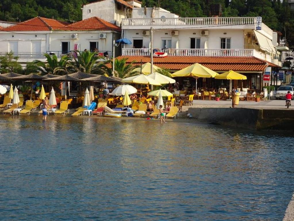 a beach with chairs and umbrellas next to the water at Aegean Hotel in Agia Triada